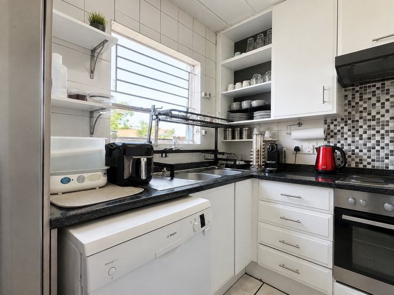 A functional kitchen featuring white cabinetry, granite countertops, a tiled backsplash, and integrated appliances including an oven and extractor fan.