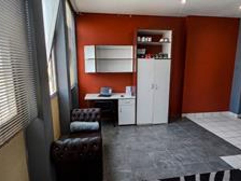 A functional office space featuring built-in cabinetry, desk workspace, venetian blinds, and tiled flooring, offering a practical area for work or study.