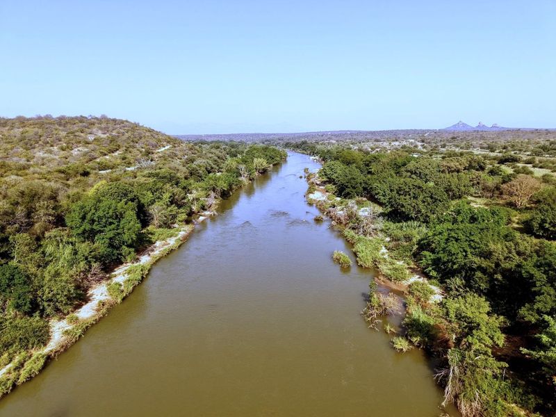 An aerial view of a natural river flowing through a lush, vegetated landscape, showcasing the scenic surroundings of the property.