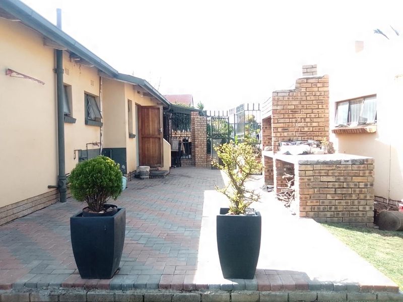 Outdoor paved patio area featuring a built-in brick braai and direct access to the rear of the property.