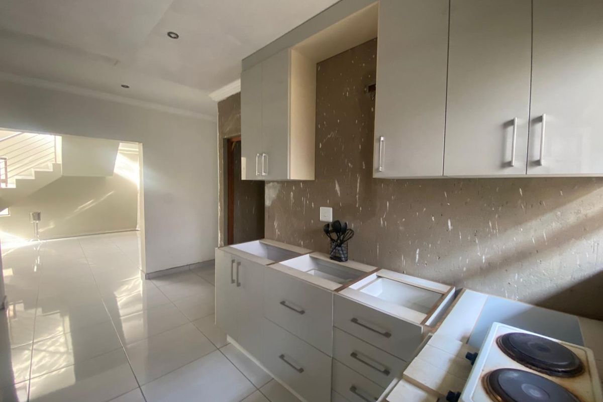 Kitchen area featuring built-in cabinetry and an electric hob, currently requiring completion of the splashback, countertop, and sink installation.