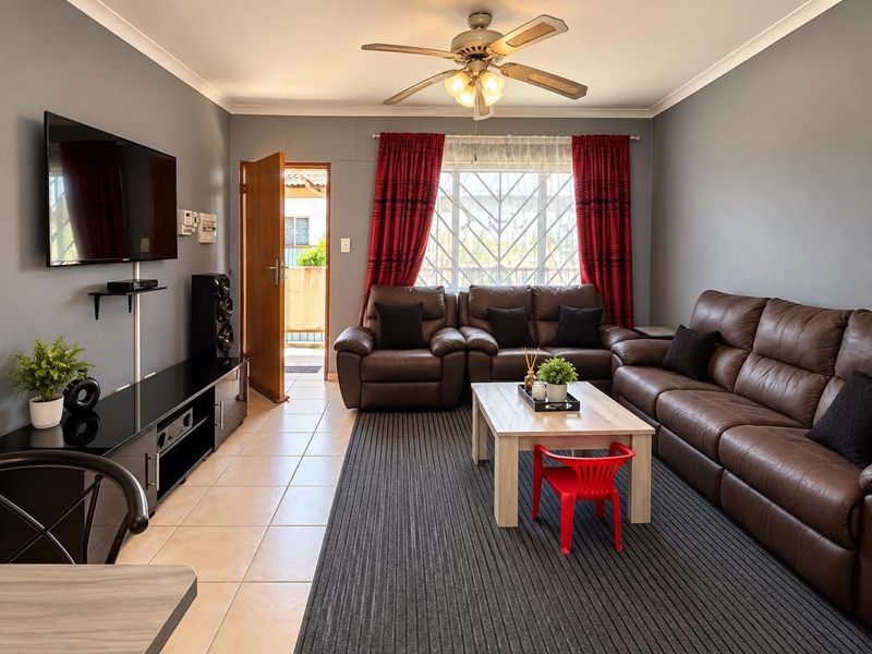 A well-maintained living room featuring tiled flooring, a ceiling fan, and direct access to an outdoor area through a secure door.