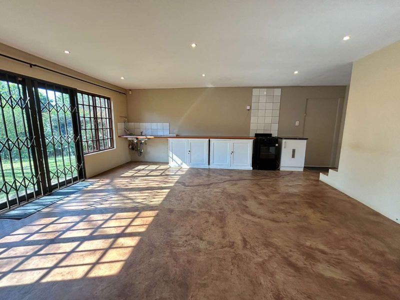 Spacious open-plan kitchen and living area featuring polished concrete floors, built-in cabinetry, and direct access to the garden through large sliding glass doors.