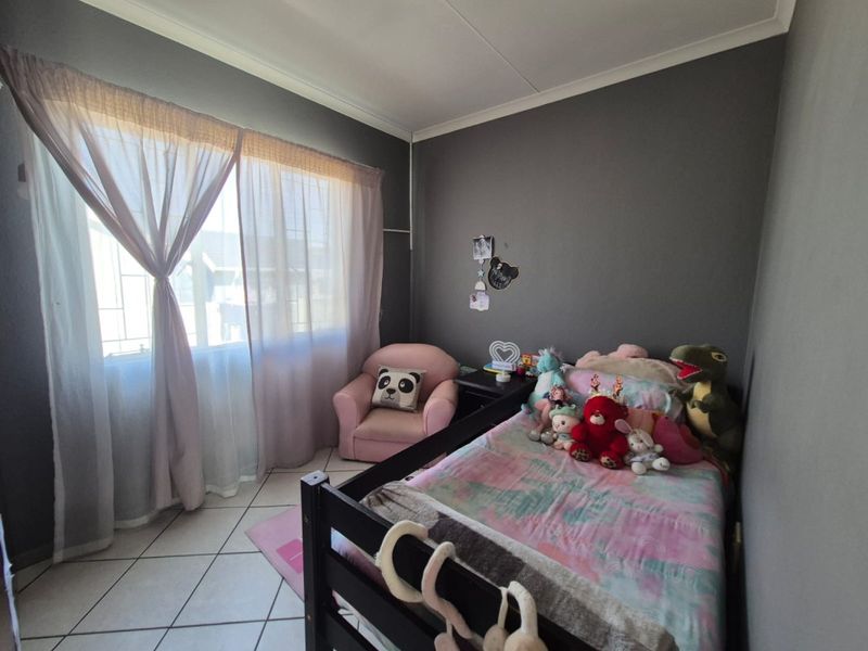 A functional bedroom featuring tiled flooring and neutral wall finishes, providing a comfortable space with natural light through the window.