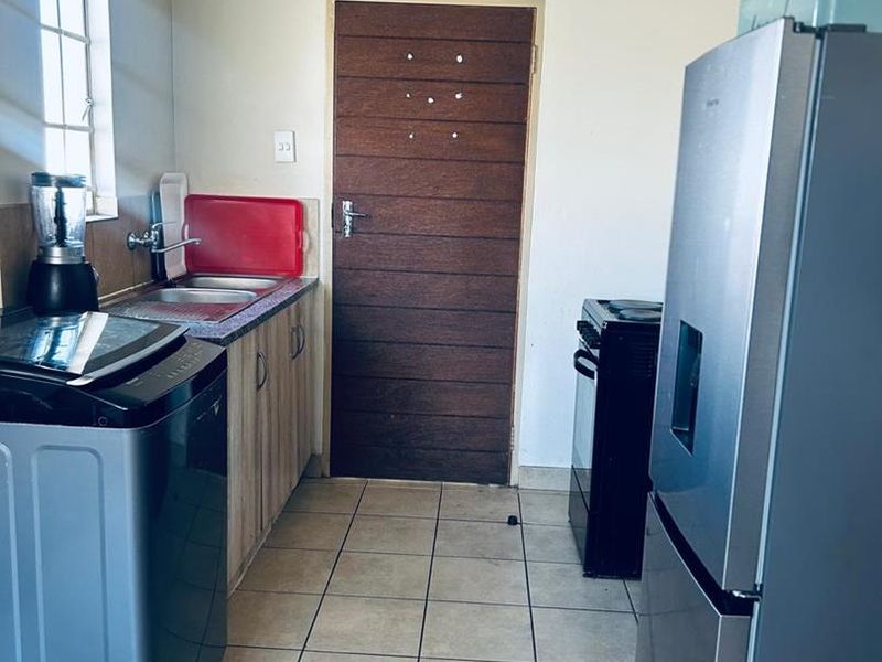 A functional kitchen area featuring tiled flooring, laminate cabinetry, and a stainless steel sink, providing a practical space for daily culinary tasks.