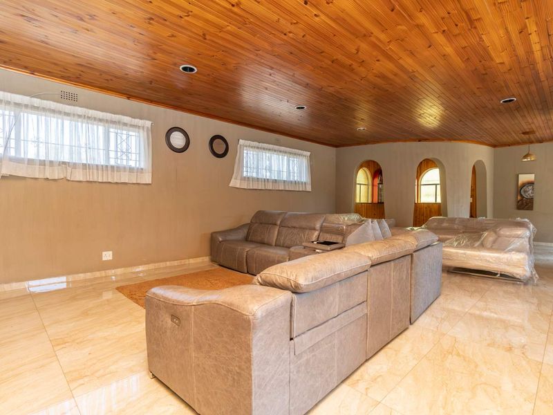 Spacious living area featuring a warm timber tongue and groove ceiling, polished tiled flooring, and distinctive arched architectural details.