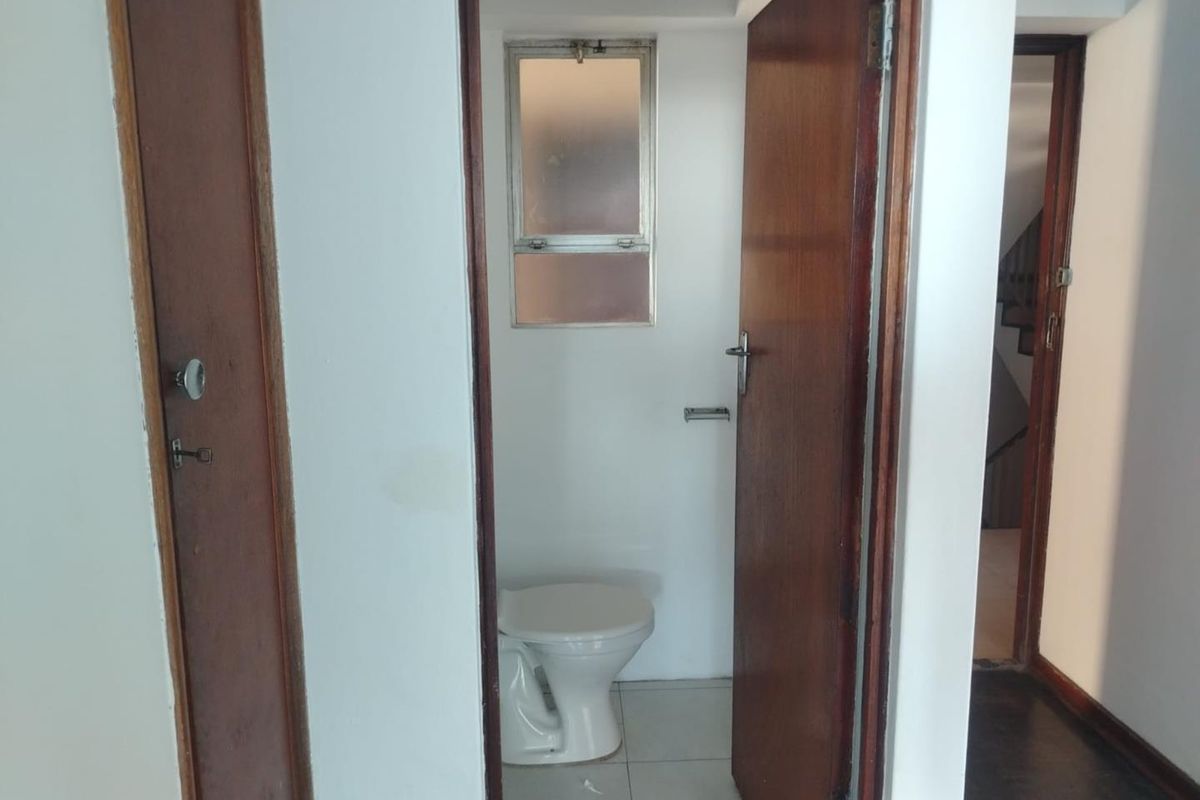 A compact, functional bathroom featuring a standard toilet, tiled flooring, and a frosted glass window for privacy.