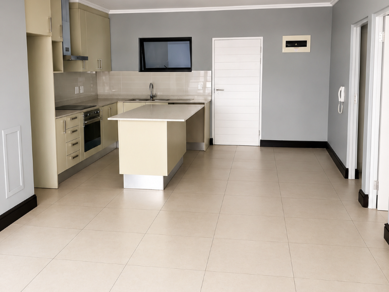 Spacious open-plan kitchen featuring modern cabinetry, a central island, built-in appliances, and neutral tiled flooring throughout.