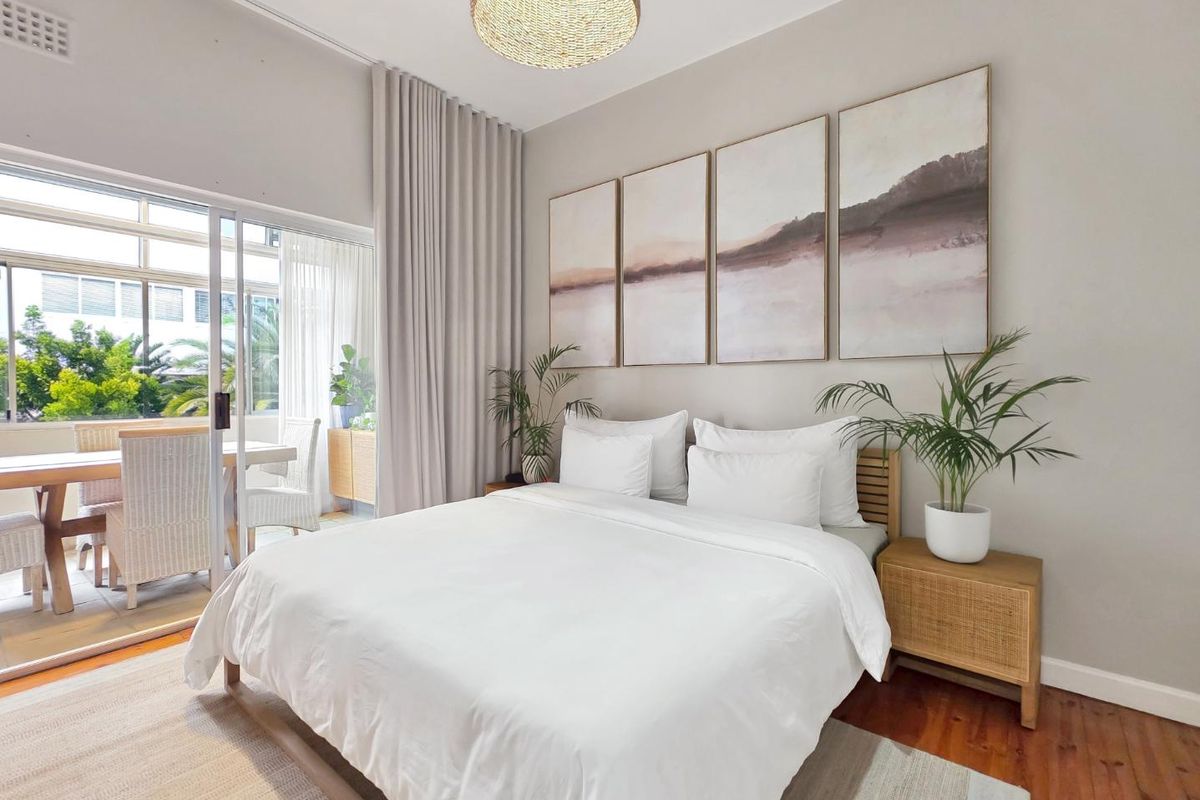 A well-lit bedroom featuring hardwood flooring and a large sliding glass door providing access to an adjoining patio area.