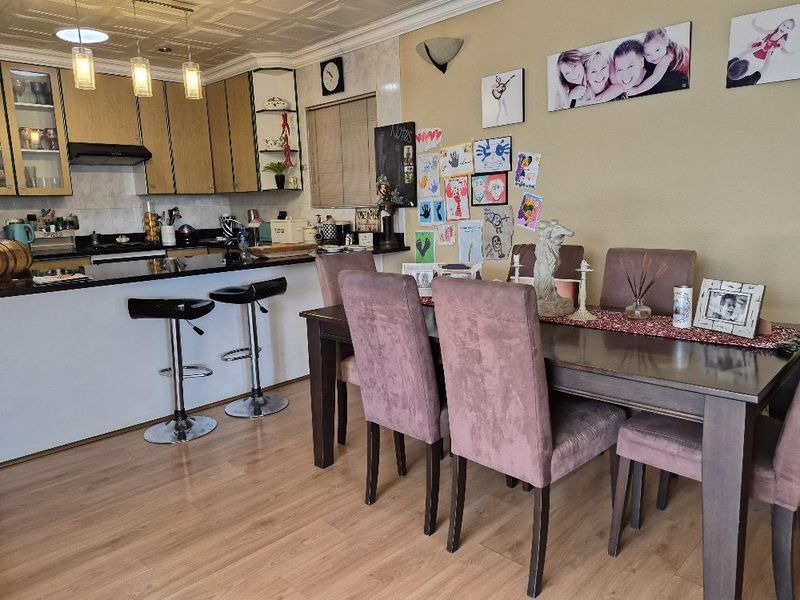 Open-plan kitchen and dining area featuring granite countertops, built-in cabinetry, and laminate flooring, creating a functional space for cooking and family meals.