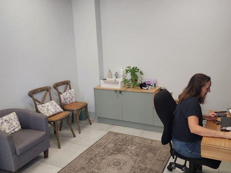 A functional office space featuring tiled flooring, a drop ceiling with recessed lighting, and a built-in vanity cabinet with an integrated sink.