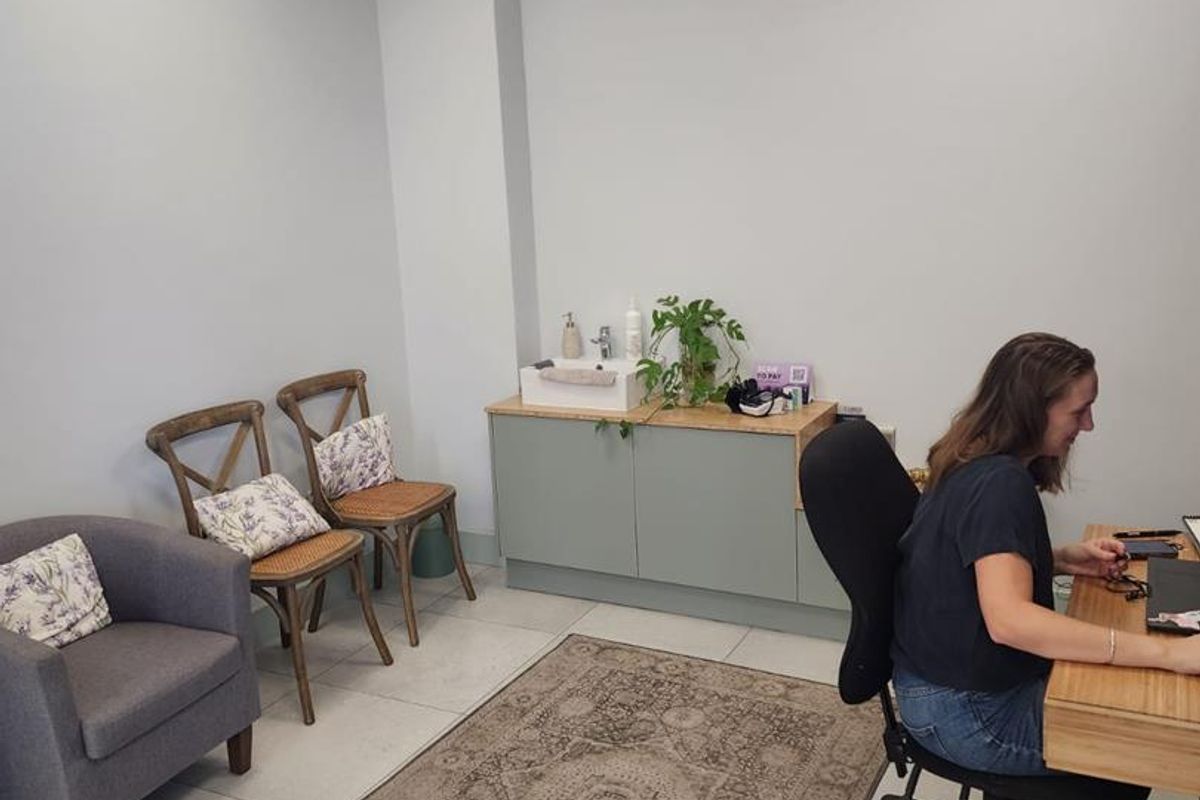 A functional office space featuring tiled flooring, a drop ceiling with recessed lighting, and a built-in vanity cabinet with an integrated sink.