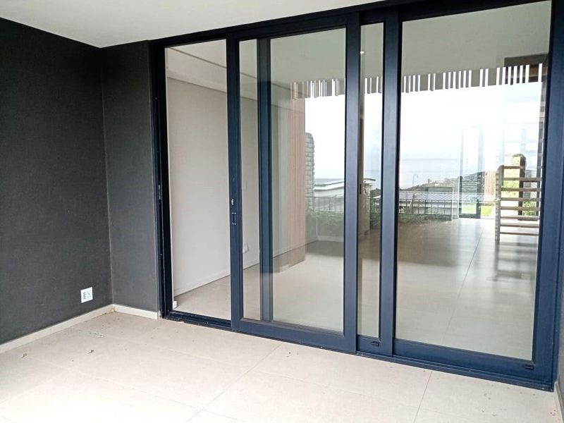A modern covered patio featuring large sliding glass doors, neutral floor tiles, and a clean, minimalist aesthetic.