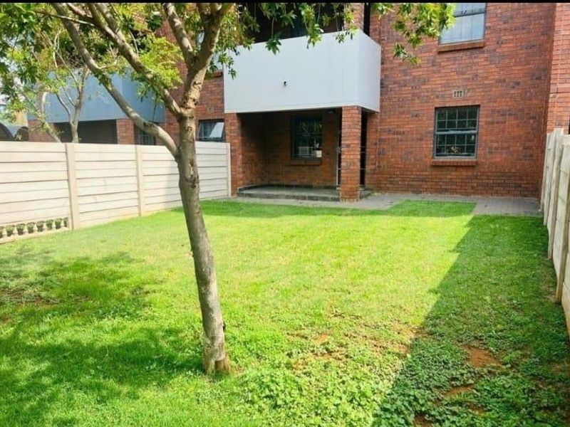 A private rear garden featuring a paved patio area, established lawn, and secure precast concrete boundary walls.