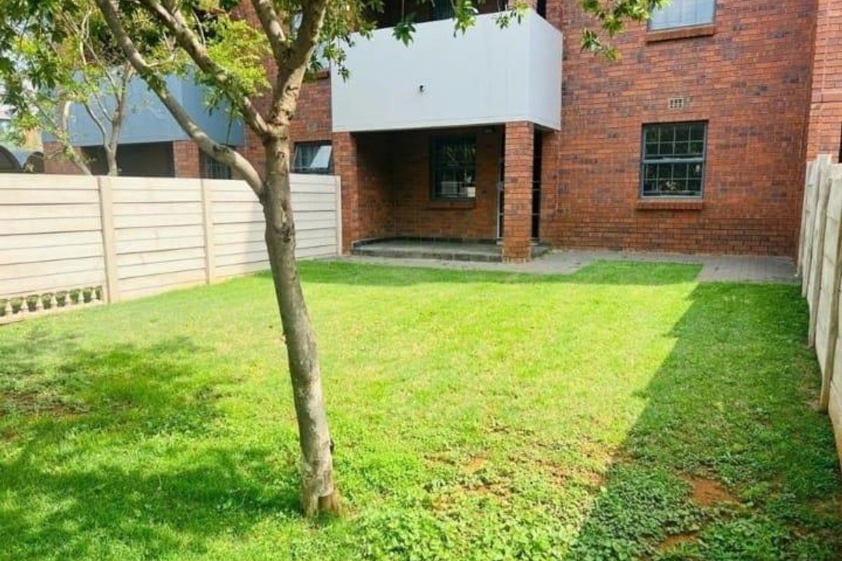 A private rear garden featuring a paved patio area, established lawn, and secure precast concrete boundary walls.