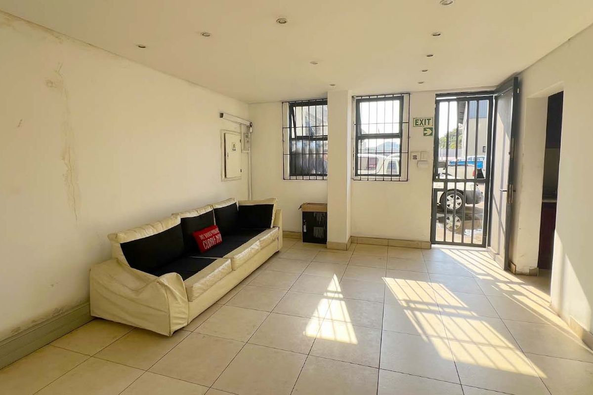 Open-plan industrial space featuring tiled flooring, security window bars, and a secure entrance gate, suitable for office or commercial use.