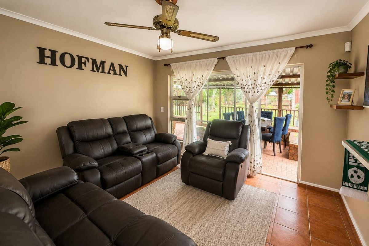 A comfortable living room featuring tiled flooring, a ceiling fan, and direct access to an outdoor patio area through sliding glass doors.