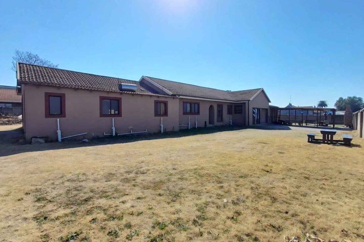 Rear view of the house featuring a tiled roof, solar water heating system, and a covered patio area overlooking the backyard.