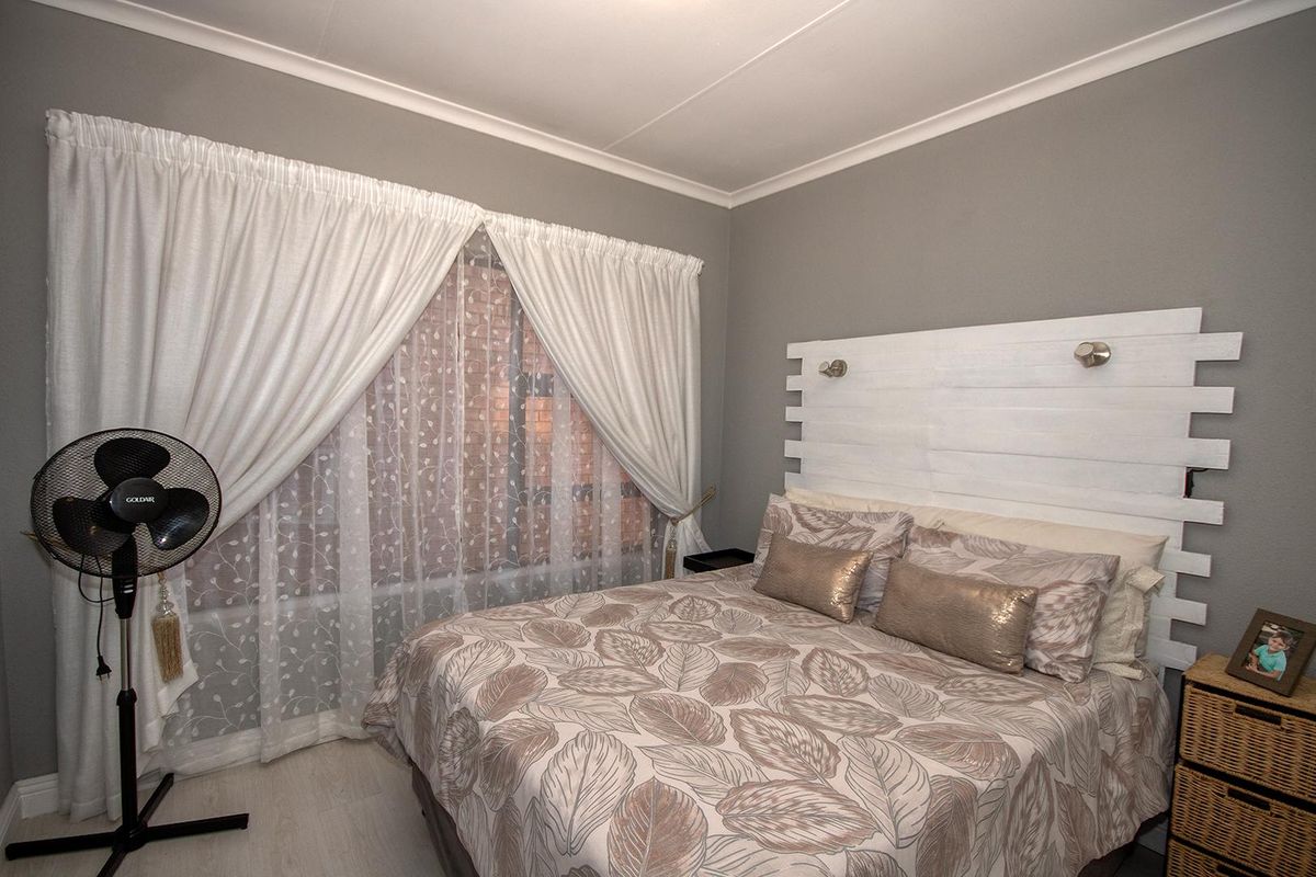 A well-maintained bedroom featuring neutral grey walls, white coving, and light-toned flooring, providing a clean and comfortable living space.