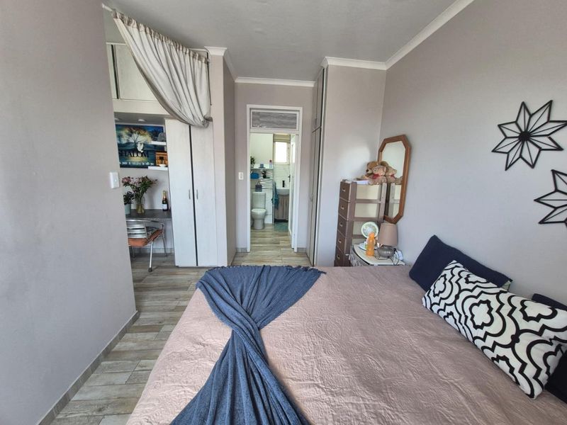 A bedroom featuring built-in cupboards, tiled flooring, and direct access to an en-suite bathroom.
