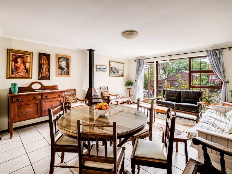 Spacious open-plan living and dining area featuring tiled flooring, a central freestanding fireplace, and large sliding doors providing access to the garden.