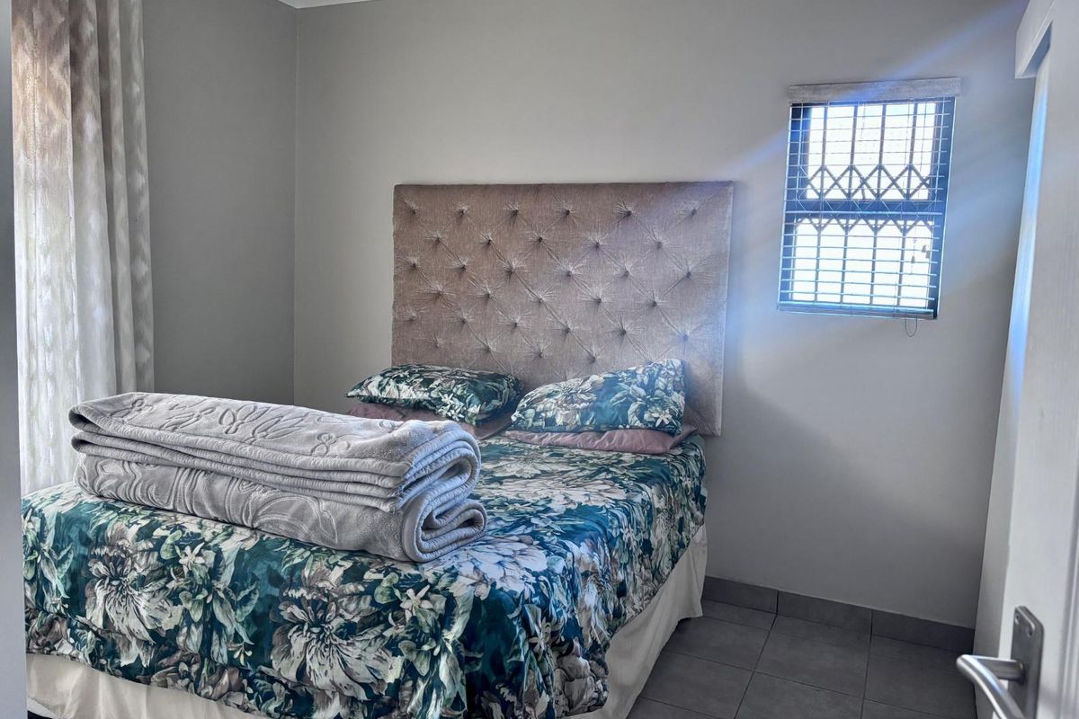 A functional bedroom featuring tiled flooring and a window fitted with security bars, providing a neutral space ready for personalization.
