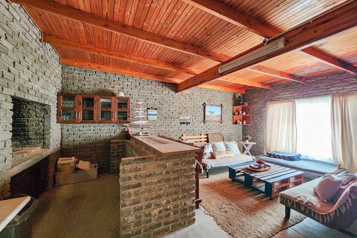 Rustic living area featuring exposed brick walls, a built-in brick fireplace, and a timber-beamed ceiling, creating a warm and character-filled entertainment space.