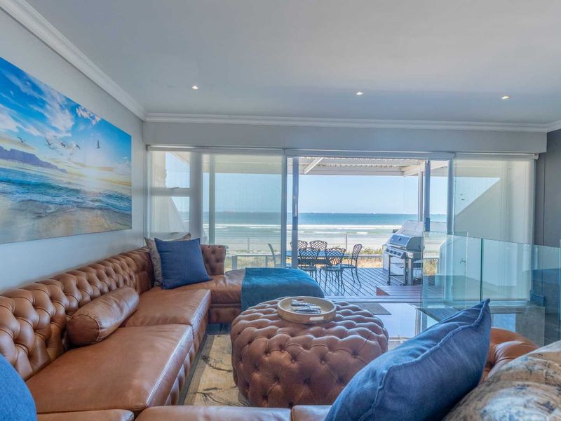 Open plan living area featuring large sliding glass doors that open onto a balcony with direct ocean views.