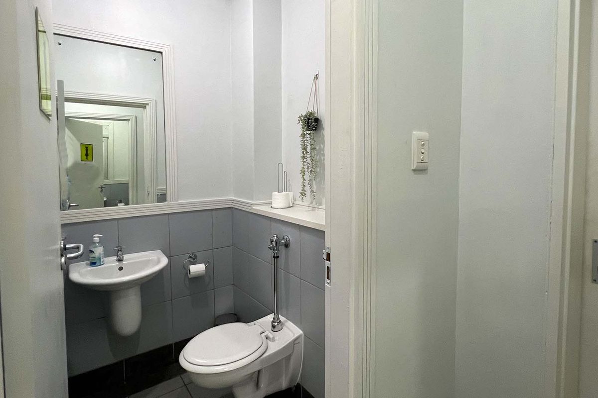 A functional guest bathroom featuring a pedestal sink, wall-mounted mirror, and toilet with a bidet spray attachment.