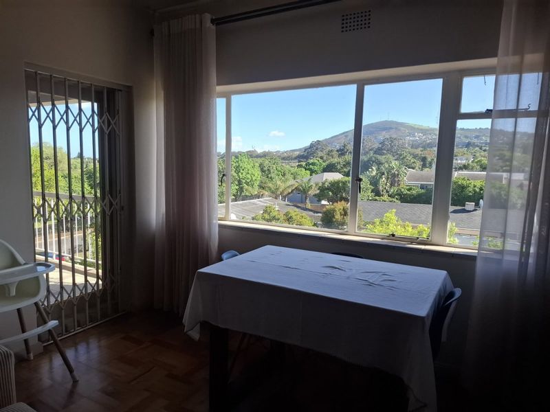 Dining area featuring parquet flooring, a large picture window with scenic views, and a sliding security gate leading to the exterior.