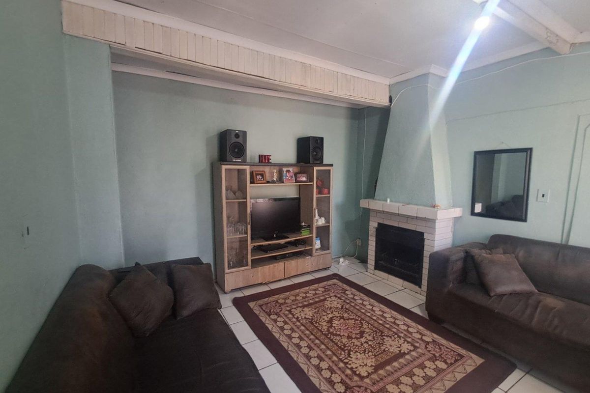 A living room featuring a built-in fireplace with a brick surround and tiled flooring, offering a functional space for relaxation.