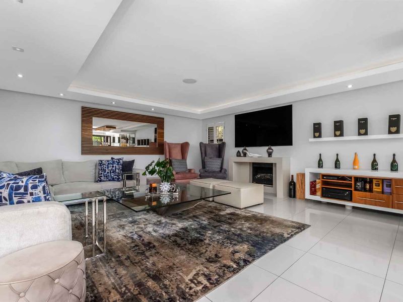 A modern, well-maintained living room featuring polished tile floors, recessed ceiling lighting, and a sleek built-in fireplace.