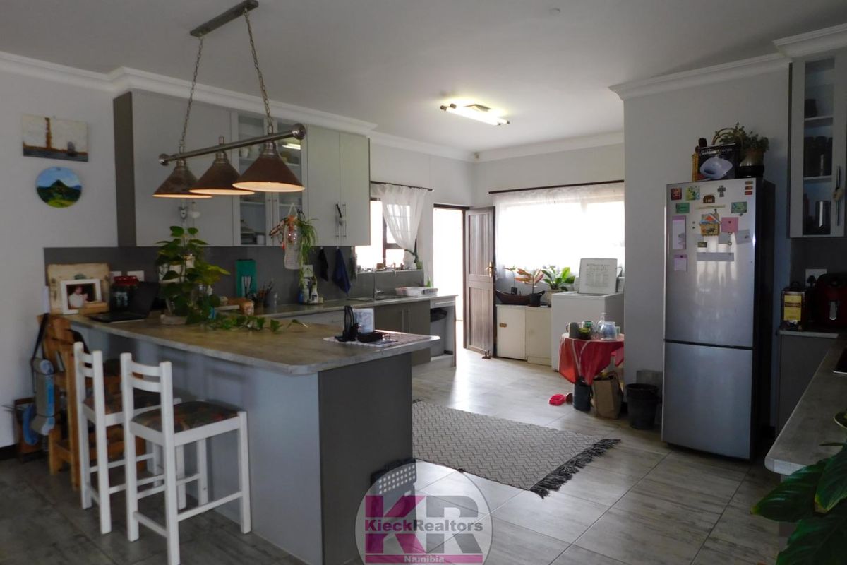 A functional kitchen featuring a central island with breakfast bar seating, modern cabinetry, and tiled flooring, offering a practical layout for daily use.