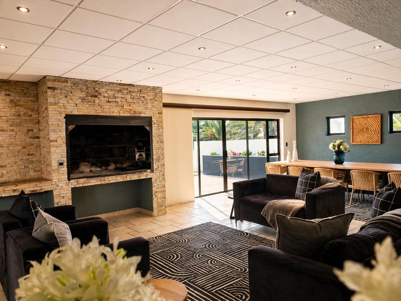 Spacious open-plan living and dining area featuring a prominent stone-clad built-in fireplace, tiled flooring, and large sliding doors leading to the outdoor patio.