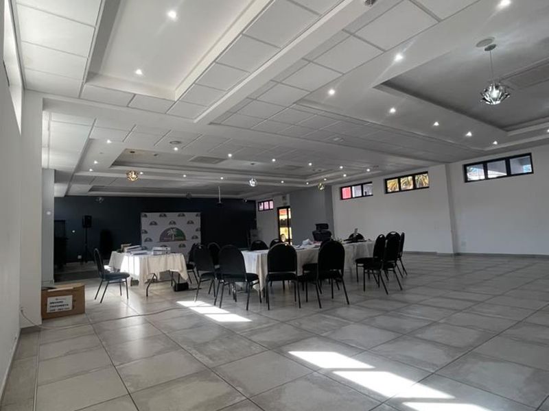 Spacious open-plan commercial area featuring large format floor tiles, recessed ceiling lighting, and high-level windows, suitable for events or office use.
