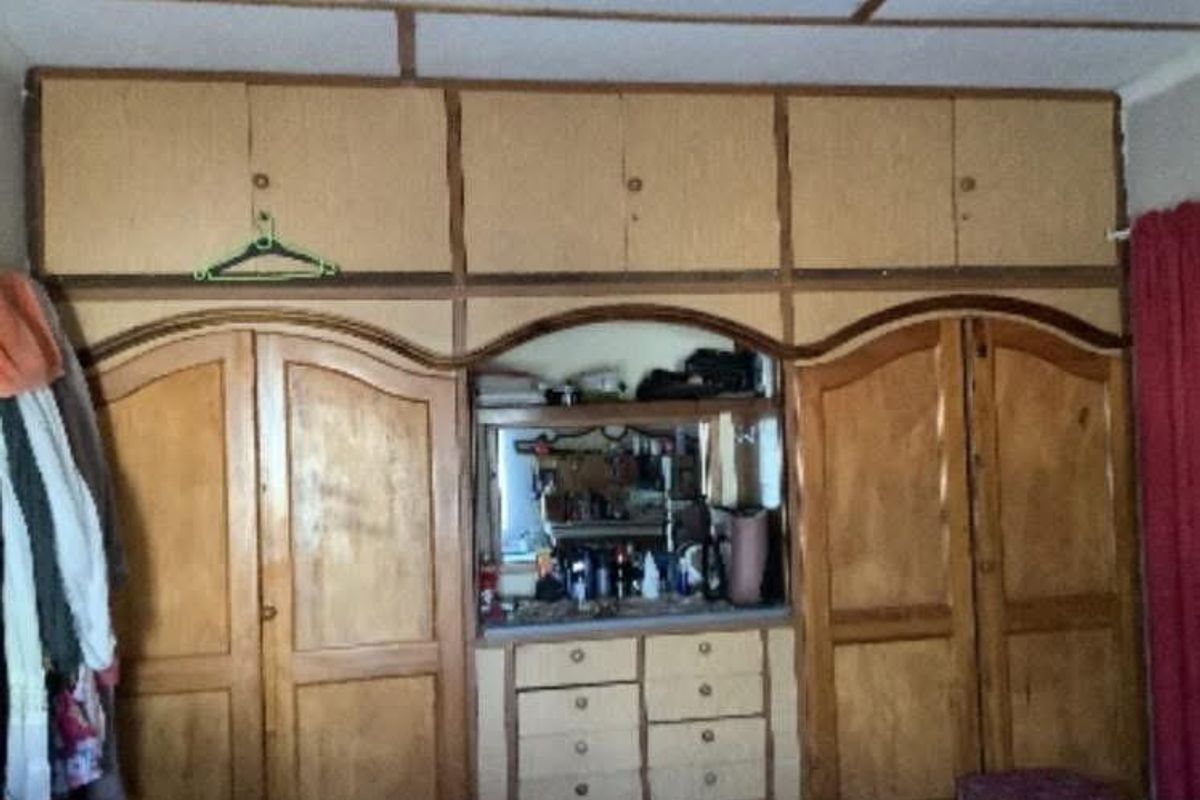 A bedroom featuring extensive built-in wooden cabinetry, including overhead storage, wardrobes, and a central vanity area with integrated drawers.