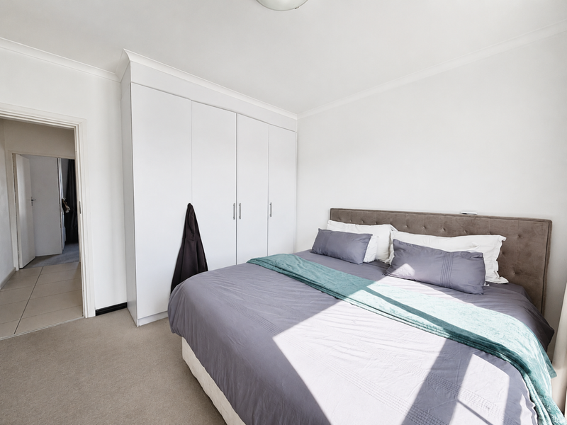 A well-maintained bedroom featuring neutral carpeting, a coved ceiling, and ample built-in cupboard storage space.