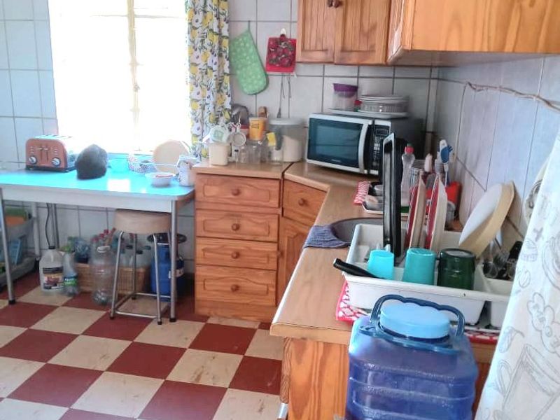 A functional kitchen featuring timber cabinetry, tiled splashbacks, and classic checkerboard flooring, offering a dated aesthetic ready for modernization.