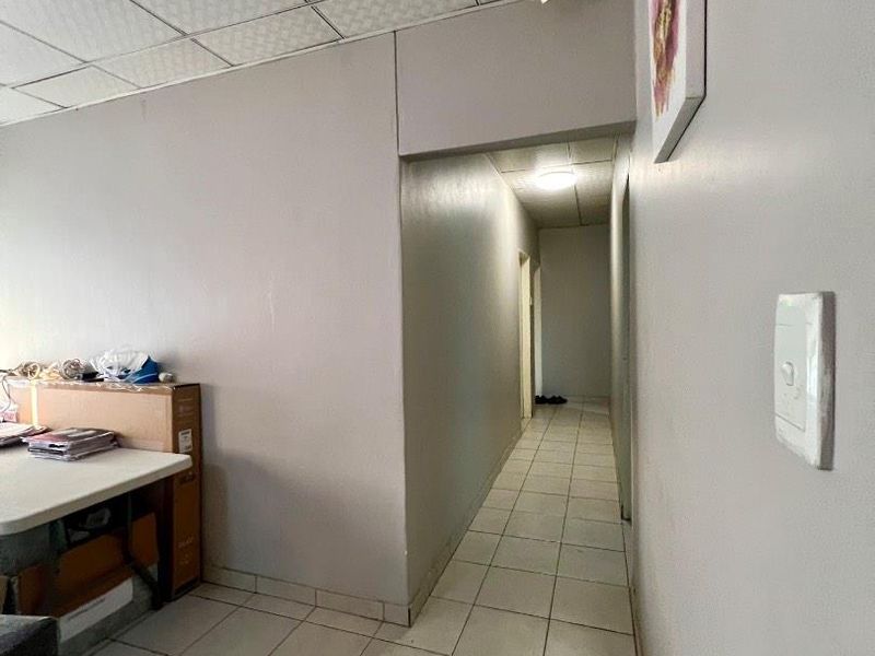 A functional hallway featuring tiled flooring and a suspended ceiling, providing access to adjacent rooms within the property.