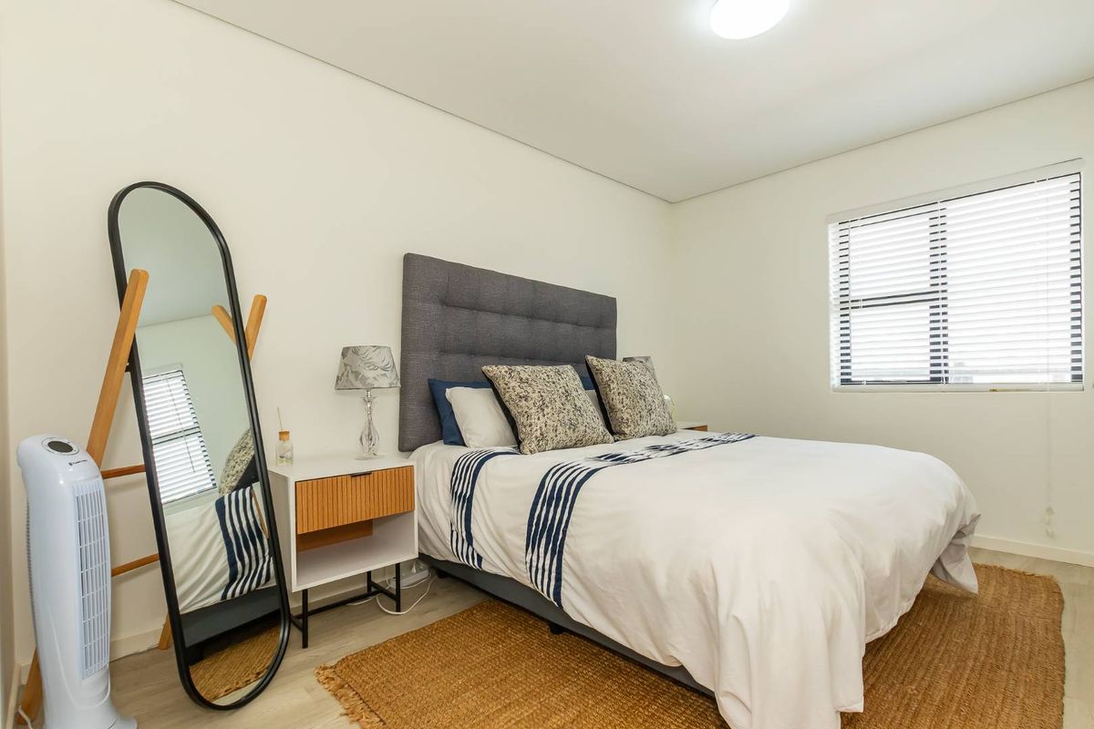 A well-maintained bedroom featuring neutral walls, light-toned flooring, and a window fitted with horizontal blinds.