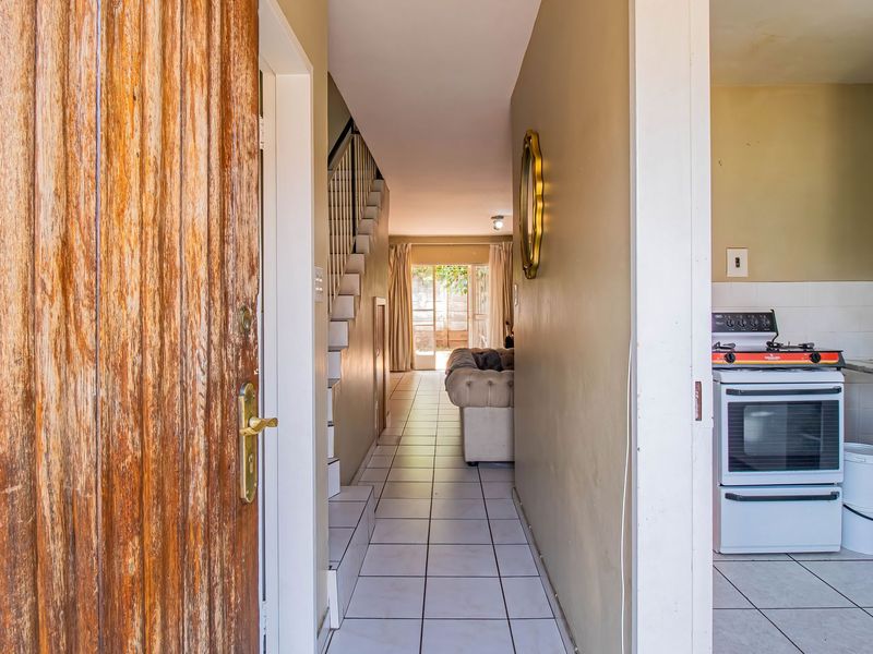 Entryway leading to an open-plan living area and kitchen, featuring tiled flooring and a staircase.