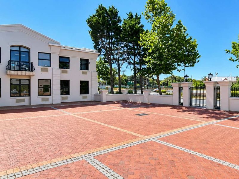 A well-maintained exterior courtyard featuring brick paving, perimeter walling with iron gates, and a multi-story office building facade.