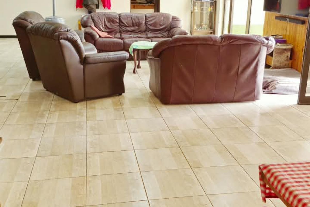Spacious living room featuring neutral tiled flooring, recessed lighting, and a wood-panelled feature wall with direct access to the outdoor area.