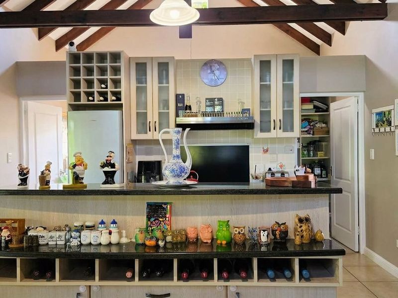 A well-appointed kitchen featuring vaulted ceilings with exposed timber beams, granite countertops, integrated wine storage, and a convenient walk-in pantry.