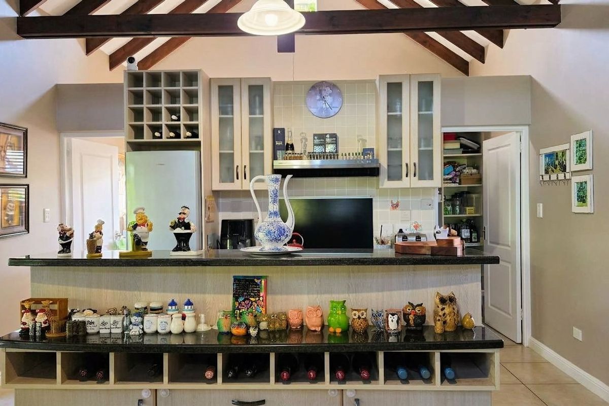 A well-appointed kitchen featuring vaulted ceilings with exposed timber beams, granite countertops, integrated wine storage, and a convenient walk-in pantry.