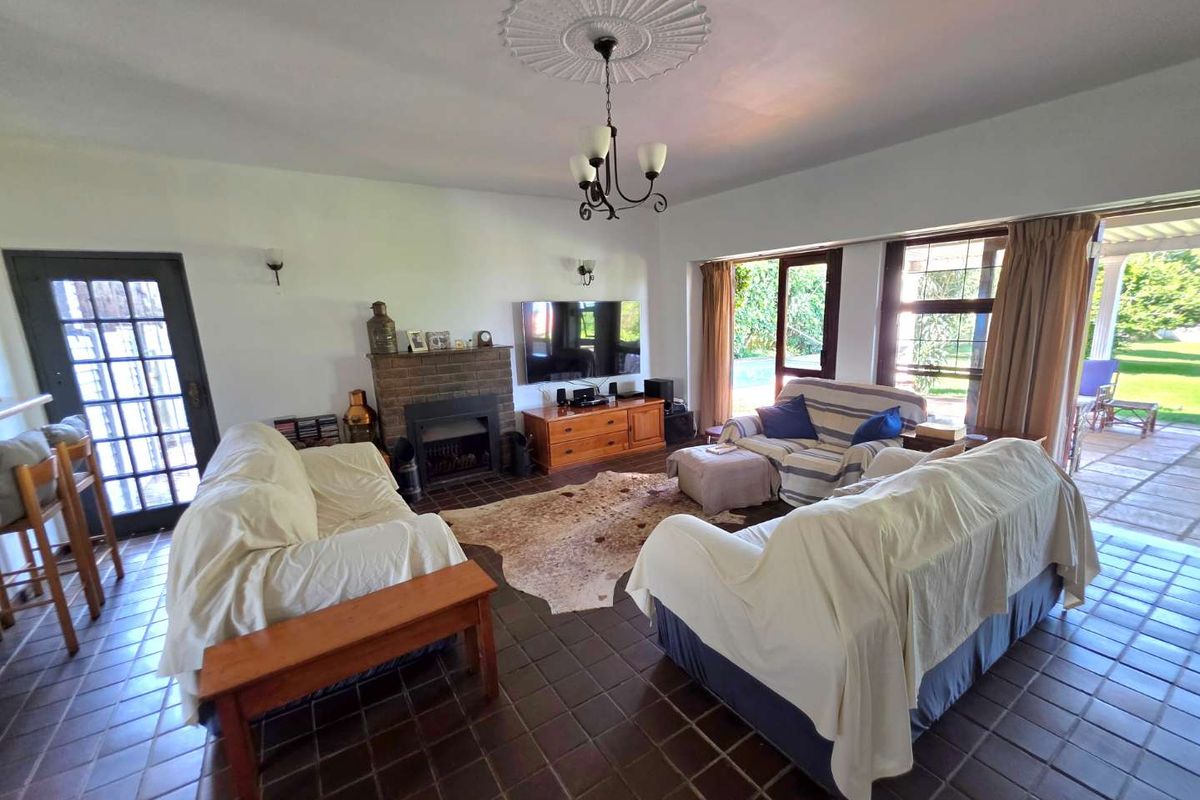 Spacious living room featuring a brick fireplace, tiled flooring, and large glass doors providing direct access to the outdoor patio and garden area.