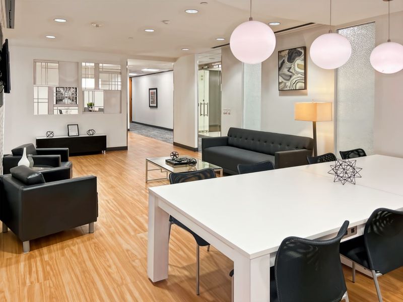 Modern professional office space featuring wood-look flooring, recessed lighting, and glass partitions, creating a bright and functional collaborative work environment.
