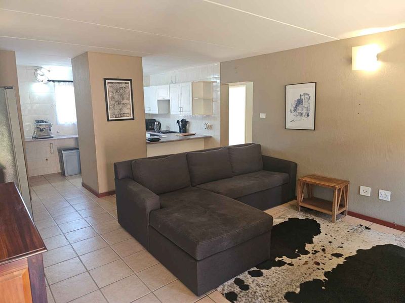 Open-plan living area featuring tiled floors and a connected kitchen space with built-in cabinetry and countertops.