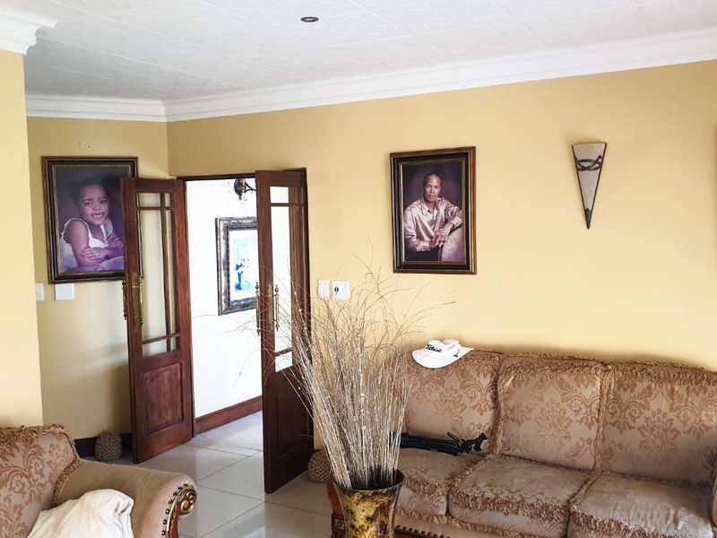 A living room featuring tiled flooring, textured ceiling, and wooden double doors leading to an adjacent space.