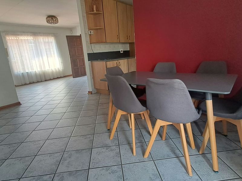 Open-plan living and dining area featuring tiled flooring and a functional kitchen with built-in cabinetry.